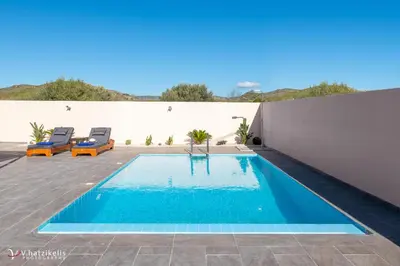 a swimming pool in the middle of a patio with two chairs at Ospition Villa in Apolakkiá