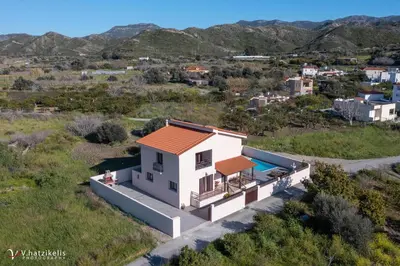 a white house with an orange roof in a field at Ospition Villa in Apolakkiá
