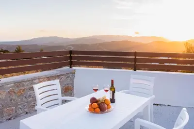 a table with two glasses of wine and a bowl of fruit at Kastrena House in Asklipiḯon