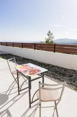 a table and a chair on a patio with a painting on it at Kastrena House in Asklipiḯon