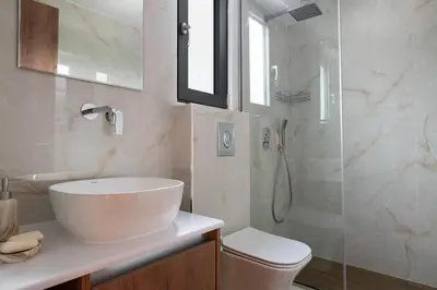 a white bathroom with a sink and a shower at Aiora Luxury Villas in Afantou