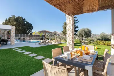 a patio with a table and chairs and a pool at Aiora Luxury Villas in Afantou
