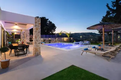 a backyard with a swimming pool and a table and chairs at Aiora Luxury Villas in Afantou