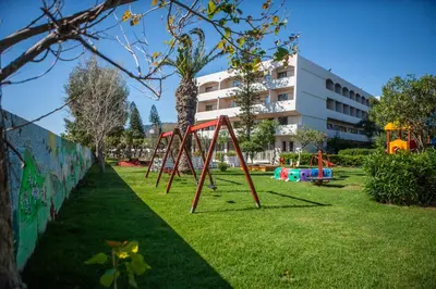 a park with a swing set in the grass at IALYSSOS BAY HOTEL in Ialyssos