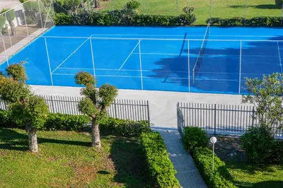 a blue swimming pool with two benches and trees at IALYSSOS BAY HOTEL in Ialyssos