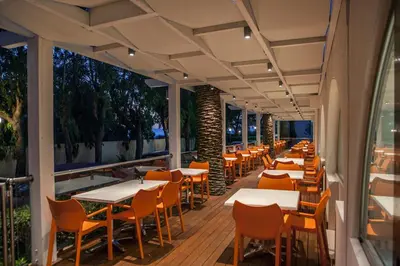 a row of tables and chairs on the deck of a restaurant at IALYSSOS BAY HOTEL in Ialyssos