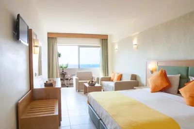 a hotel room with a bed and a living room at IALYSSOS BAY HOTEL in Ialyssos