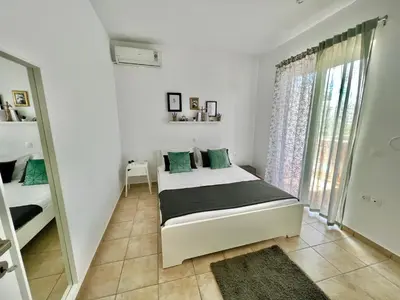 a white bedroom with a bed and a window at Cute & sweet home in Archangelos