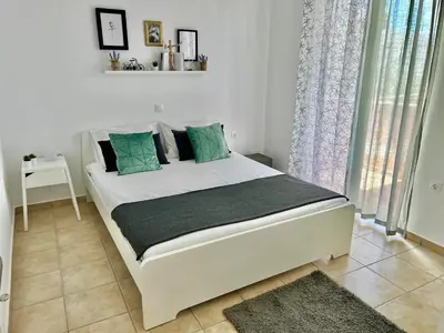 a bedroom with a white bed with green pillows at Cute & sweet home in Archangelos