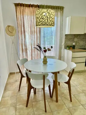 a white dining room table with chairs and a vase with flowers at Cute & sweet home in Archangelos