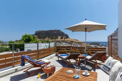 a patio with a table and chairs and an umbrella at LindosaquaView Luxury villa in Líndos