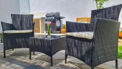 three chairs and a table with a vase of flowers at Lefko House in Lachania