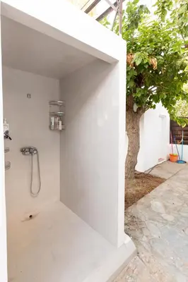 a shower in a white wall next to a tree at Katerlove Beach House in Faliraki