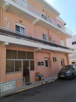 a car parked in front of a pink building at IRINIS HOUSES in Rhodes Town