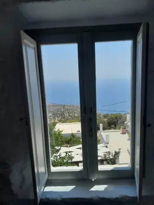 an open glass door with a view of a building at Oniropagida Nisyros apartments #2 Nikia view in Nikiá