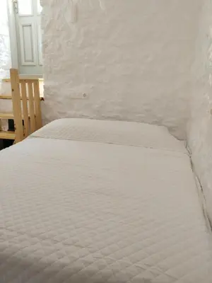 a white bed in a bedroom with a white wall at Oniropagida Nisyros apartments #2 Nikia view in Nikiá