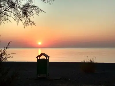 a garbage can on the beach with the sunset in the background at Stella Luxury Apartment Kalathos in Kalathos