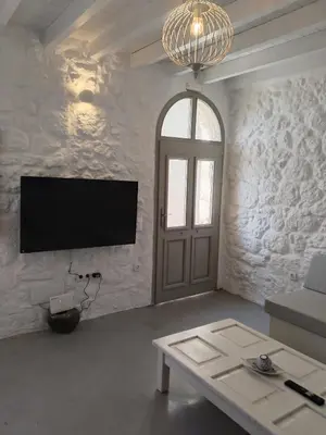 a living room with a flat screen tv and a door at Oniropagida Nisyros apartment #1 in Nikiá