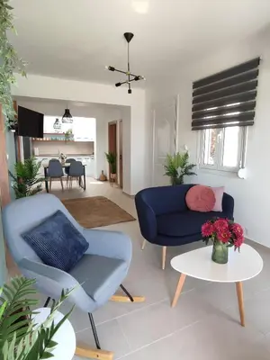 a living room with a blue couch and a table at Kalokairini Avra in Archangelos