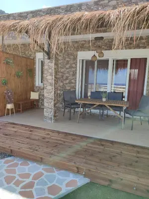 a patio with a table and chairs and a straw roof at Kalokairini Avra in Archangelos