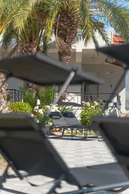 a group of chairs sitting in front of a palm tree at Propodes Luxury Villa in Pastida