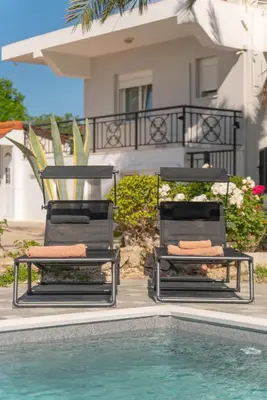 two chairs sitting next to a swimming pool at Propodes Luxury Villa in Pastida