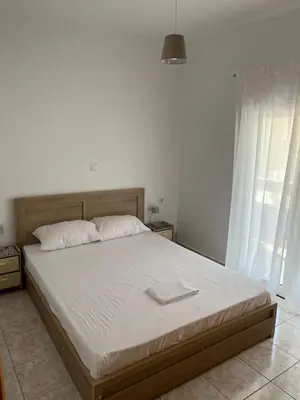 a bedroom with a large bed with white sheets at G.S Ialysos Holiday Apartment in Ialyssos