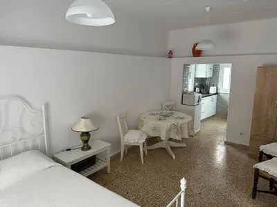 a bedroom with a table and a bed and a kitchen at Blue and White in Kremasti