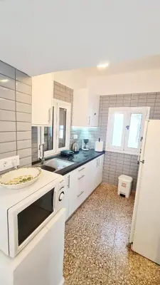a white kitchen with a sink and a refrigerator at Blue and White in Kremasti