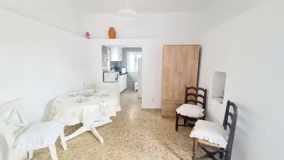 a white room with two tables and chairs and a kitchen at Blue and White in Kremasti