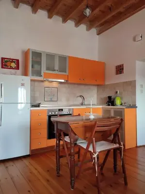 a kitchen with a wooden table and a white refrigerator at Omorfo House in Asklipiḯon