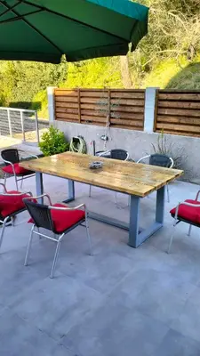 a large wooden table with chairs and an umbrella at Green Heaven in Koskinou