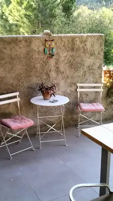 a patio with two chairs and a table and a table and benches at Green Heaven in Koskinou