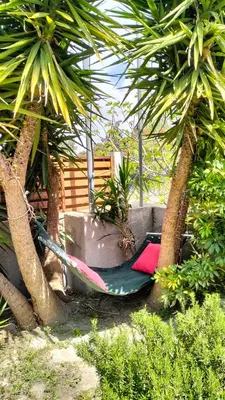 a hammock between two palm trees in a garden at Green Heaven in Koskinou