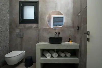 a bathroom with a sink and a toilet and a mirror at Nόka Suite Apartments in Faliraki