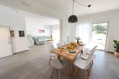 a dining room with a wooden table and white chairs at Euphoria Blue Villa στην περιοχή Ιξιά in Rhodes Town