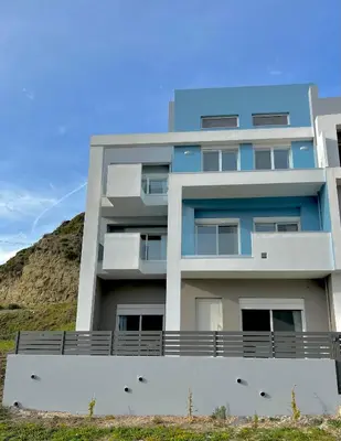 an apartment building with a hill in the background at Euphoria Blue Villa στην περιοχή Ιξιά in Rhodes Town