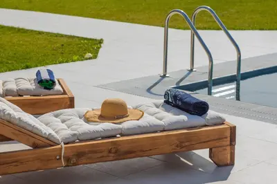 a wooden bench with a hat next to a swimming pool at Villa Cervus Dianae in Kallithea Rhodes