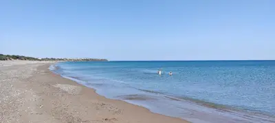 two people swimming in the water on a beach at el greco apartment in Rhodes Town