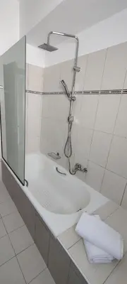 a bathroom with a shower and a tub with a mirror at el greco apartment in Rhodes Town