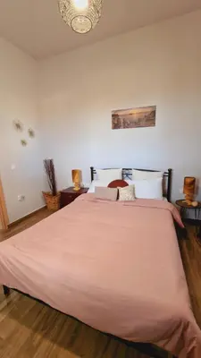 a bedroom with a large bed with a pink blanket at Seva Monolithos house in Monólithos