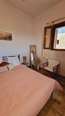 a bedroom with a bed and a mirror and a window at Seva Monolithos house in Monólithos