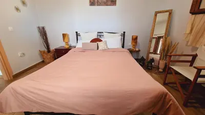 a bedroom with a large bed with a orange blanket at Seva Monolithos house in Monólithos