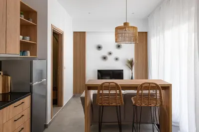 a kitchen with a wooden table and two chairs at Venthos Apartments in Kolimbia