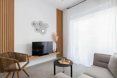 a living room with a tv and a chair and a table at Venthos Apartments in Kolimbia