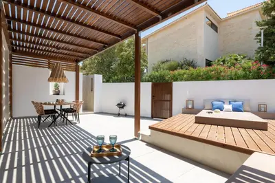 a patio with a wooden pergola and a table at Venthos Apartments in Kolimbia