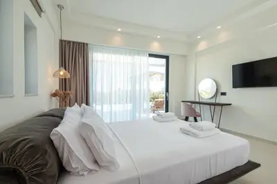 a bedroom with a large white bed with a television at Gatsby Rhodes -Two Brand New Exclusive Villas in Asgourou