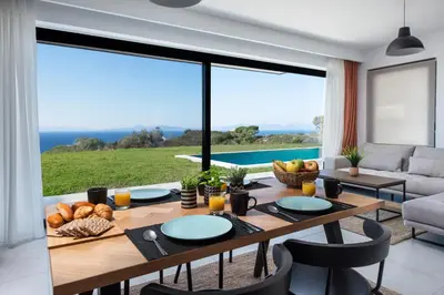 a dining room with a table and a view of the ocean at Aquarama Pool Apartments in Ixia