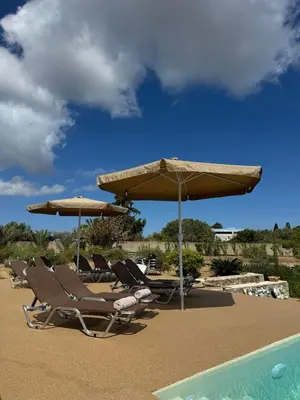 a group of chairs and umbrellas next to a pool at Home21 in Asgourou