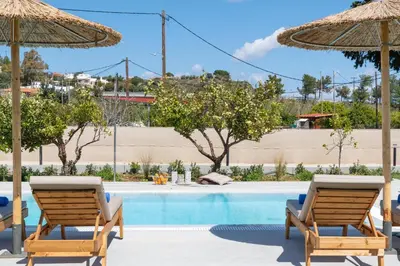 a swimming pool with two chairs and umbrellas at Ethria Pool Villa with heated jacuzzi in Afantou